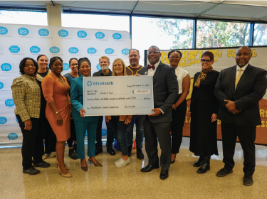 chapman standing in a group with big check